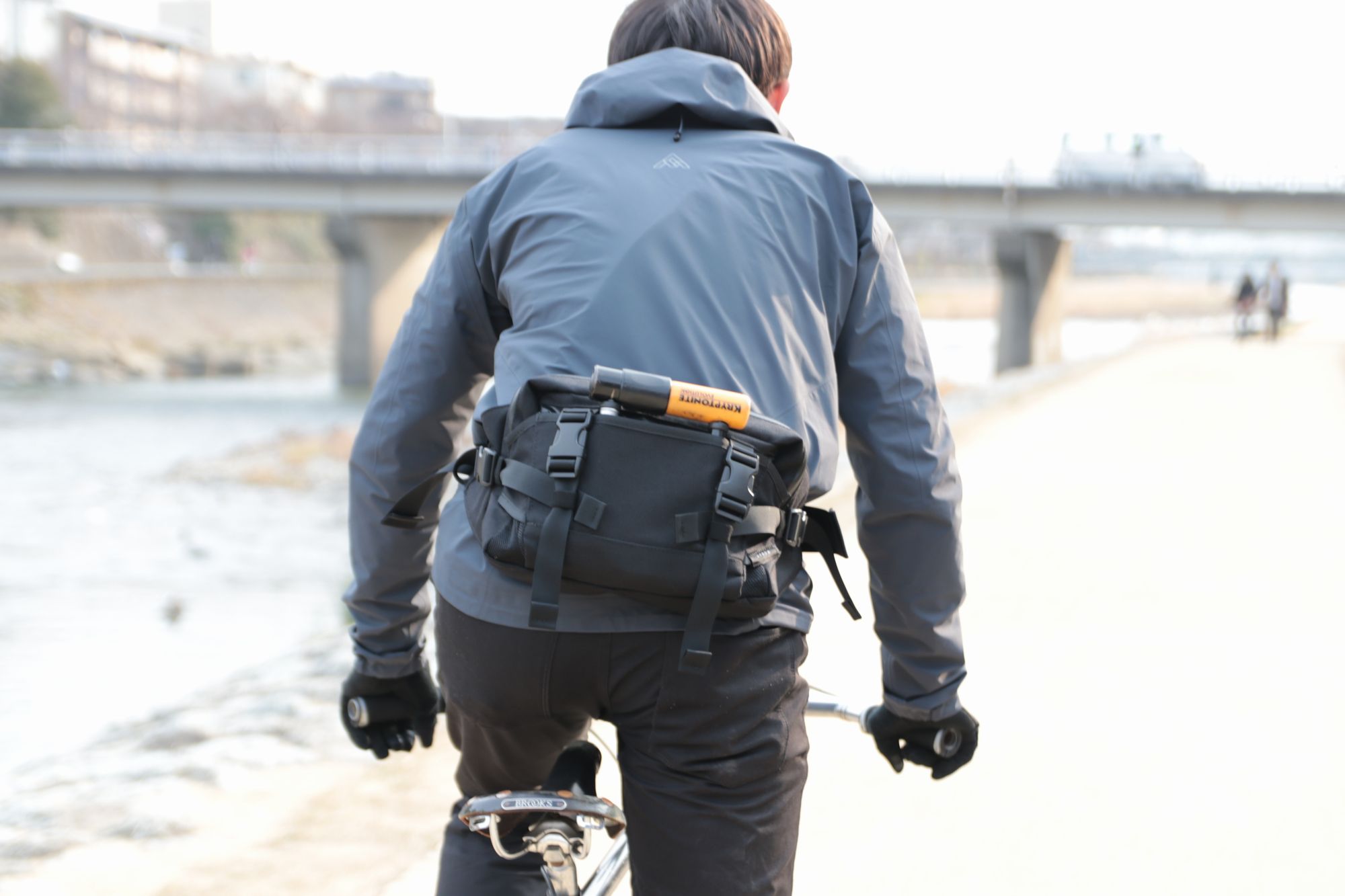 HYNOW（ハイノウ）のウェストバックDACK PACK（ダックパック）を付けて鴨川沿いを自転車で走る後ろ姿