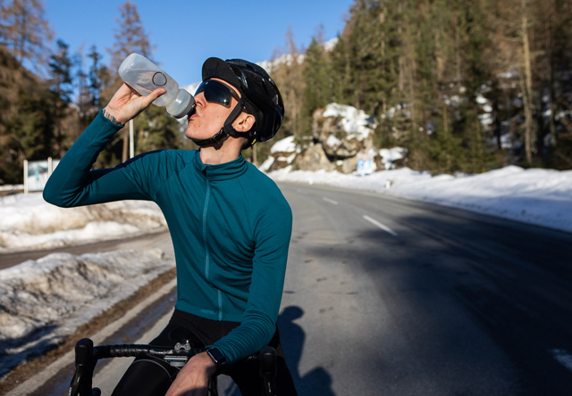 イザドアのサイクルジャージを羽織り水を飲む男性